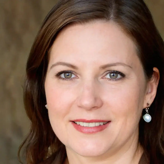 Boucles d'oreilles goutte de perle avec une chaîne de ton argenté et un petit élément décoratif.