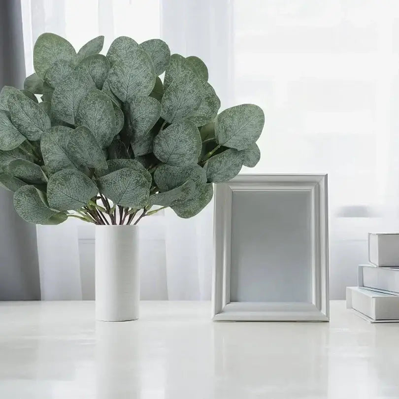 Arrangement luxuriante de branches d’eucalyptus artificielles dans un vase blanc cylindrique élégant