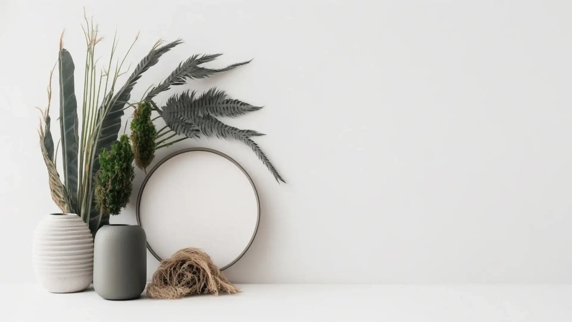 Deux vases en céramique à finition mate, l'un avec des stries verticales et l'autre lisse, contiennent une composition de verdure séchée sur un fond blanc.